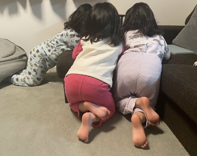 1台のタブレット型端末を一緒にのぞく三つ子