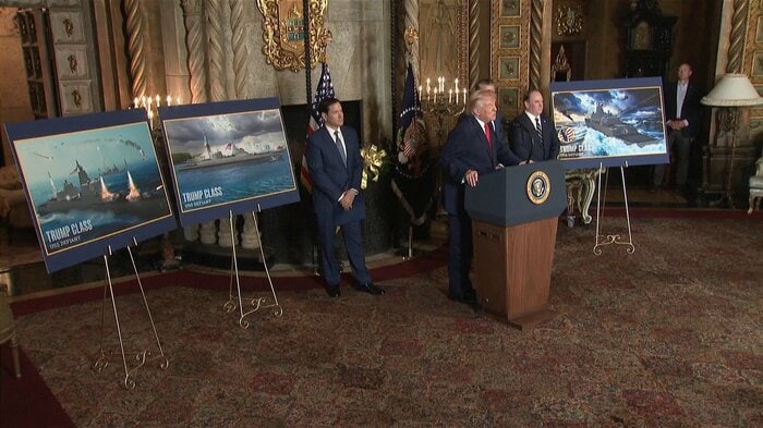 トランプ級戦艦“デフィアント”完成予想図の前でスピーチするトランプ大統領（12/22）