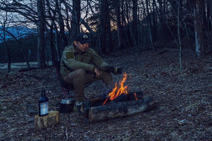 ハンター型の焚き火で暖を取る伊澤さん（『焚き火の教科書』より）