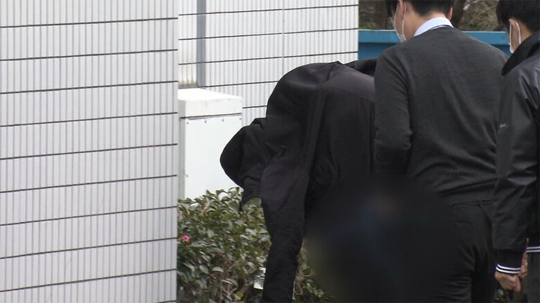 藤枝署に連行される津田奨太容疑者。上着を頭からかぶり表情はうかがえなかった(24日)