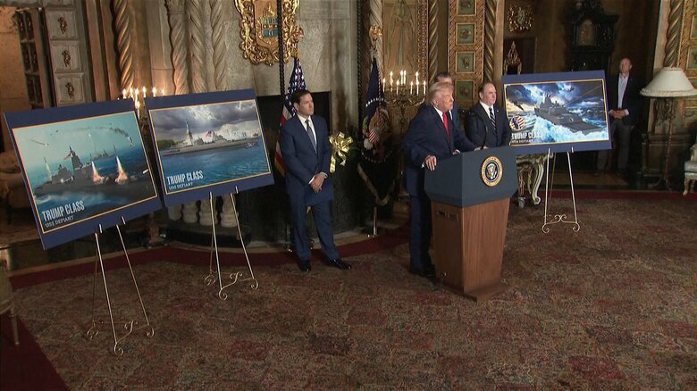 トランプ級戦艦“デフィアント”完成予想図の前でスピーチするトランプ大統領（12/22）