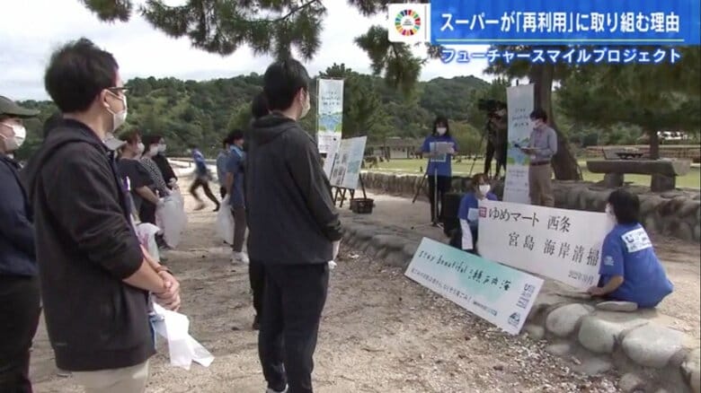 宮島の包ヶ浦海水浴場に整列する食品スーパーのスタッフ