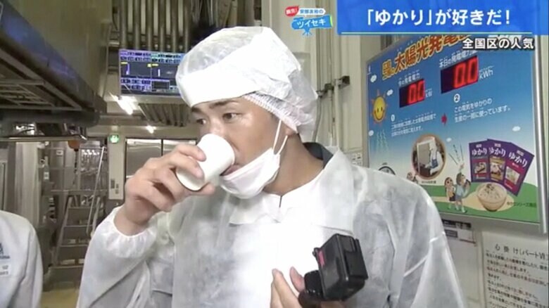 紙コップに注いだ赤紫色の液体を飲む安部さん