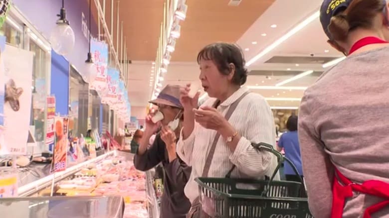 店頭でイガイの出汁を試飲する買い物客