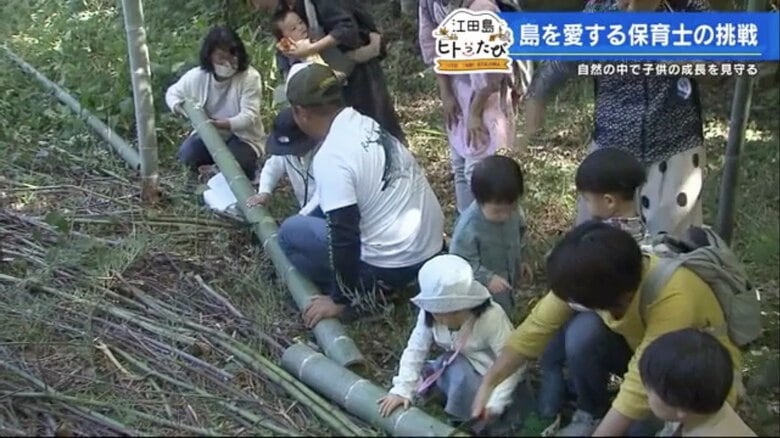 倒した竹をのこぎりで運びやすい大きさに切る子どもたち