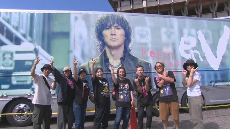 稲葉さんを写す大型看板を前に記念撮影するファン