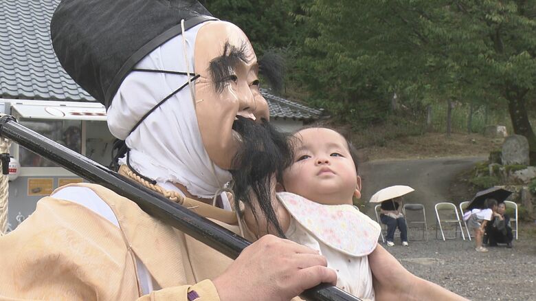 ひげをつかみじっと見つめる赤ちゃん