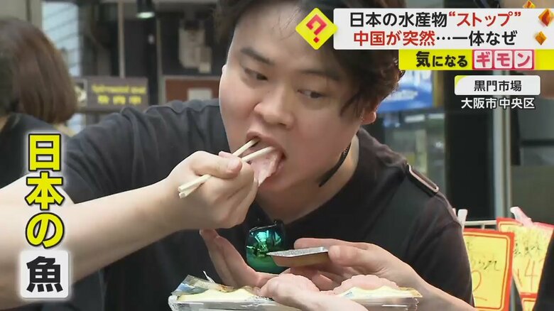 大阪市中央区の黒門市場で刺身を食べる外国人観光客