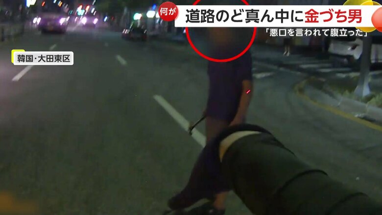 多くの車が走る道路の真ん中にいた右手に金づちを持った男