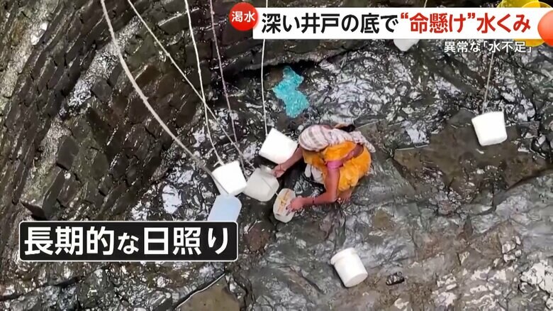 井戸の底でわずかに染み出てきた水をすくう女性