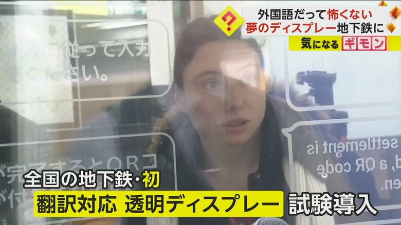 翻訳対応透明ディスプレーで駅員とコミュニケーションをとる外国人
