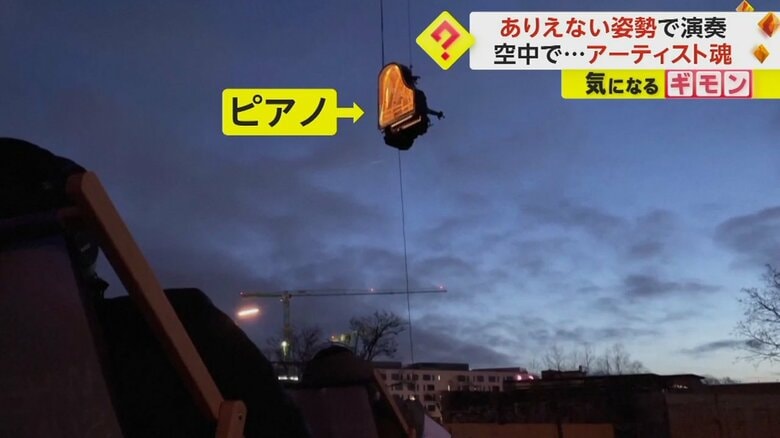 宙に浮いたピアノを見上げる人