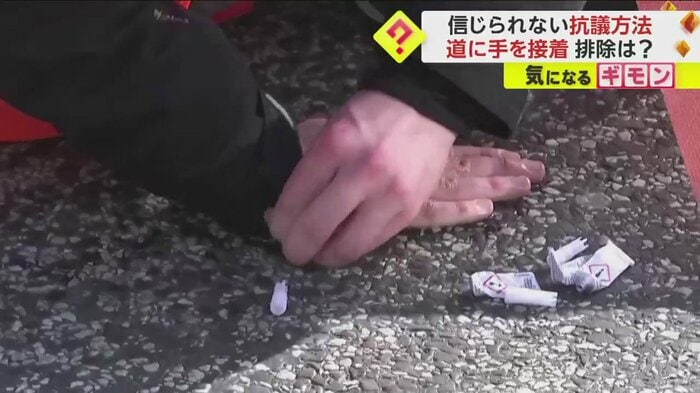 接着剤で手を道路に貼り付ける環境活動家