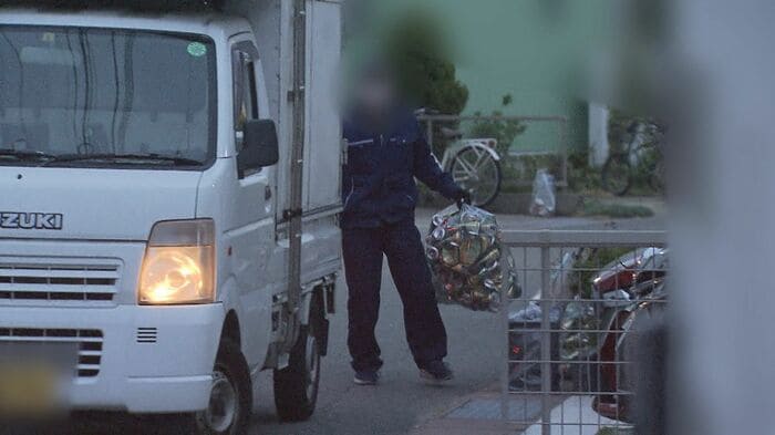 アルミ缶が入った袋をトラックに積み込む男性