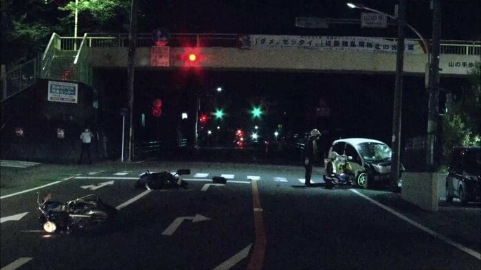 事件発生直後の現場 右端の白い軽自動車が手前のバイクをはねた