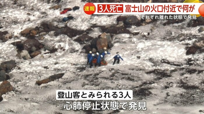 雪が残る火口付近で、捜索隊とみられる人々が担架のような物を運び出していた