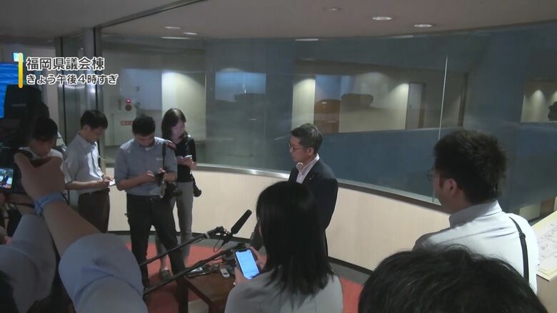 記者団に辞任を表明する松尾会長(8月3日)