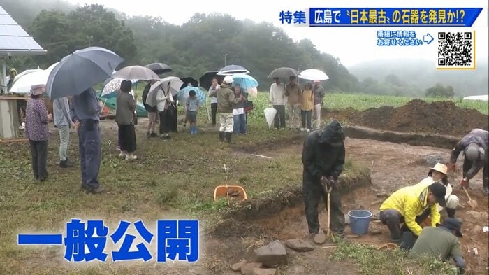 雨の中、発掘現場を見学する人々