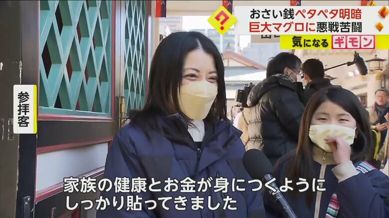 招福マグロについて話す参拝客の親子