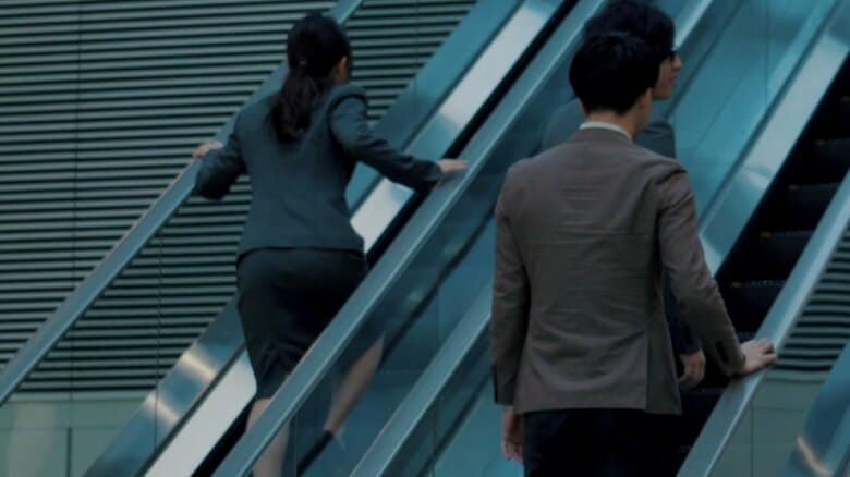 隣にある上りのエスカレーターに乗った男性に追い越されます