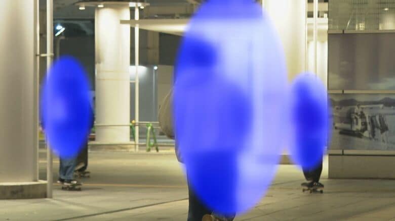 パトカーに気付き走り去るスケートボーダー