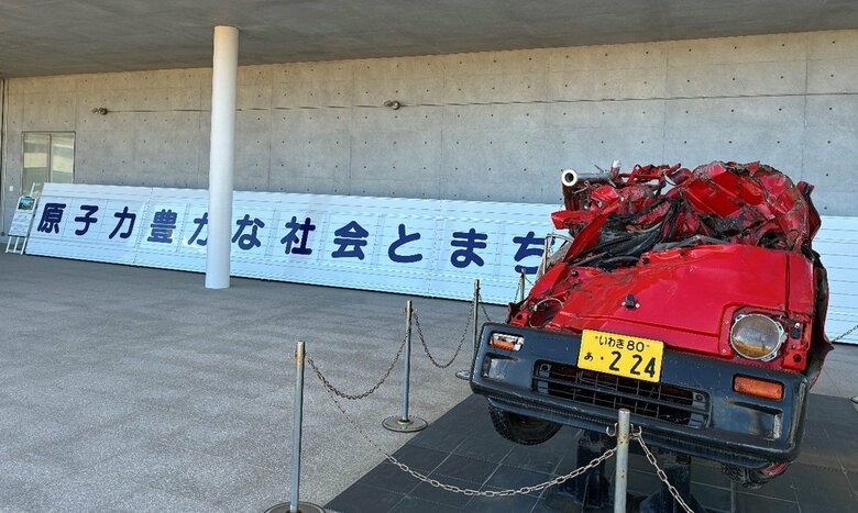 東日本大震災・原子力災害伝承館（双葉町） 津波被害で原型をとどめない消防車と双葉町内に設置されていた標語パネルの実物大レプリカ（筆者撮影）