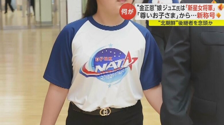 金総書記とともに、軍事偵察衛星の打ち上げ成功を祝う宴会に出席したジュエ氏とみられる娘。Tシャツには「NATA」と書かれたロゴ。