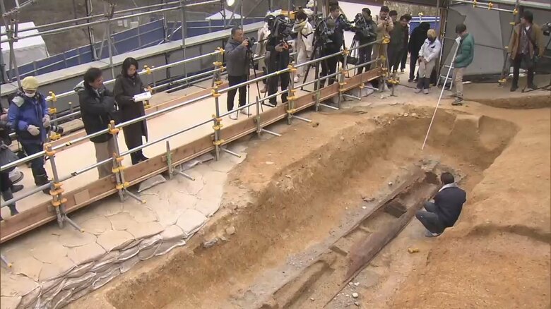 出土された木棺を撮影する報道陣