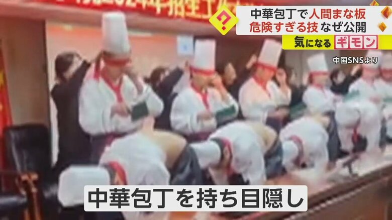 服をまくり上げ、体を90度に曲げた状態で一列に並ぶ人たち