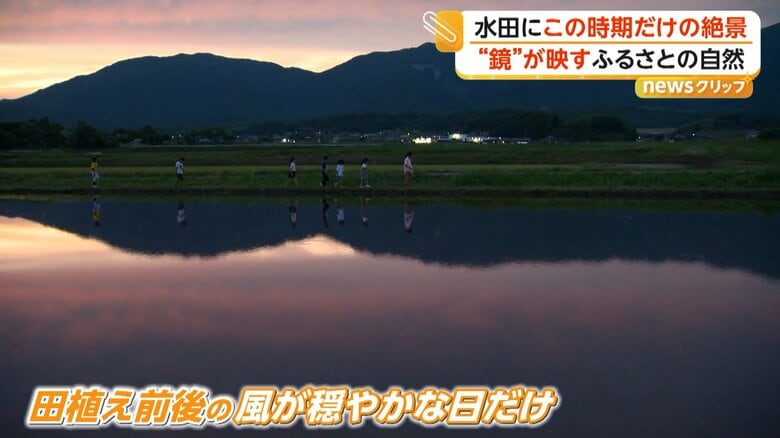 田植え前後に水を張った田んぼへ夕焼けや山々が映り込む幻想的な景色