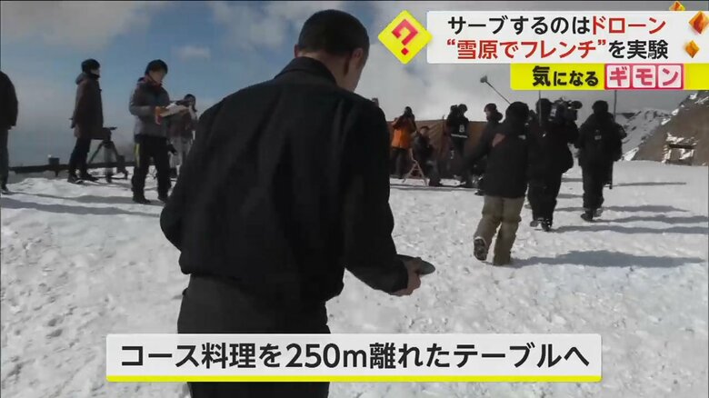 ドローンが運んできた料理をサーブする人