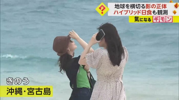 部分日食を見ようと、空を見上げる女性