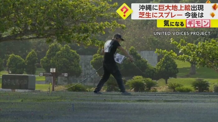 芝生にスプレーのようなものを吹きかける、帽子姿の男性