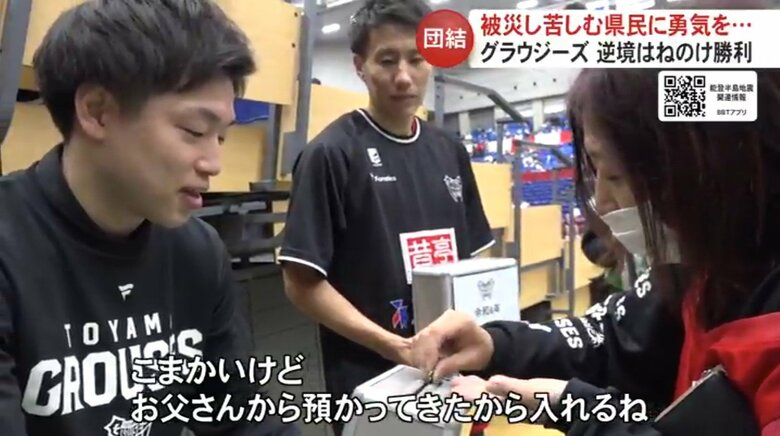 募金する来場者（右）と富山グラウジーズ　通訳兼練習生　酒井達晶さん（左）
