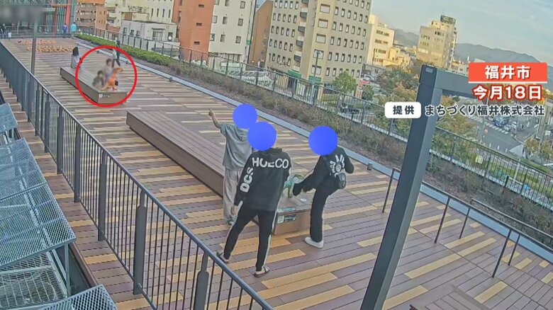 奥には、3人組の犯行を驚いた様子で見ている親子らしき姿も