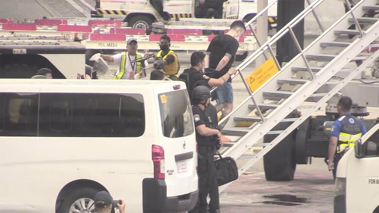日本に向かう航空機に乗せられる藤田聖也容疑者