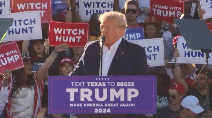 トランプ氏の背面には「魔女狩り」のプラカード持った支持者らもいた