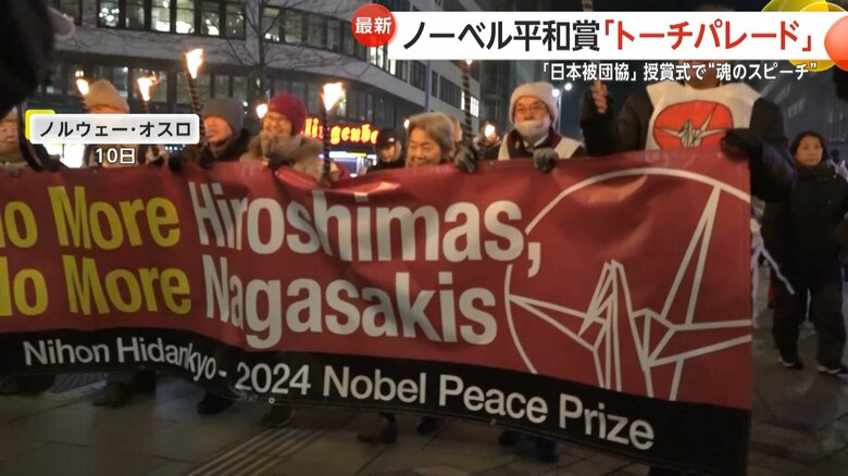 「No More Hiroshima」と書かれた横断幕を手にするパレード参加者