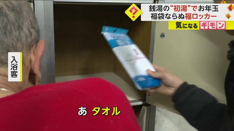 “福ロッカー”から体を洗うタオルを取り出し喜ぶ入浴客
