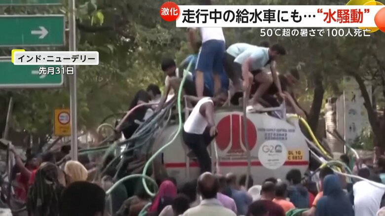 給水車の上に乗りホースを伸ばす住民