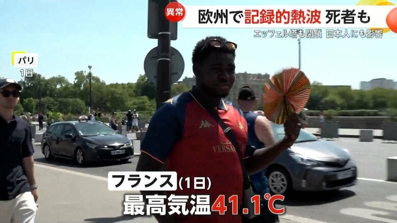 うちわであおぎながら外を歩く人（7月1日、フランス・パリ）