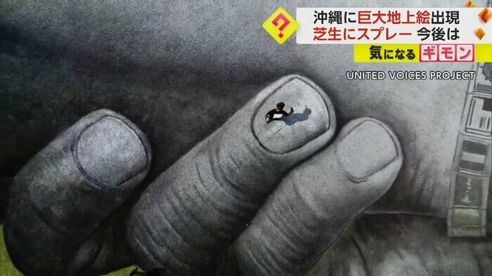 上空からの映像。人の指がスプレーで描かれている