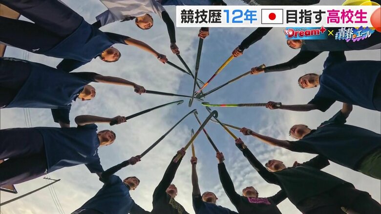 ホッケーのスティックを掲げエンジン組む様子