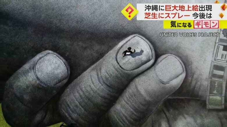 上空からの映像。人の指がスプレーで描かれている