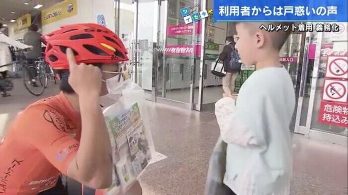 子どもに啓発グッズを手渡す地元自転車チームの選手