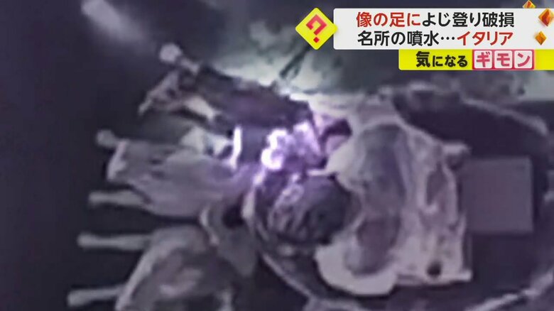像の足元に座り込んで、両足を伸ばす男性