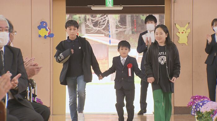 6年生と手をつなぎ入学式の会場に入る柳沢丈くん(中央・4月6日)