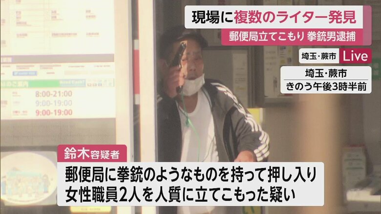 立てこもっていた郵便局から姿を見せ、拳銃のようなものを上げて威嚇するような動きを見せる鈴木容疑者（31日）