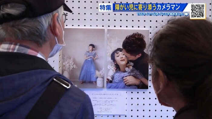 障がい児とその家族の写真を見つめる来場者