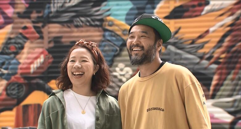 完成した壁画の前で撮影に応じるDragon76さんと綾子さん